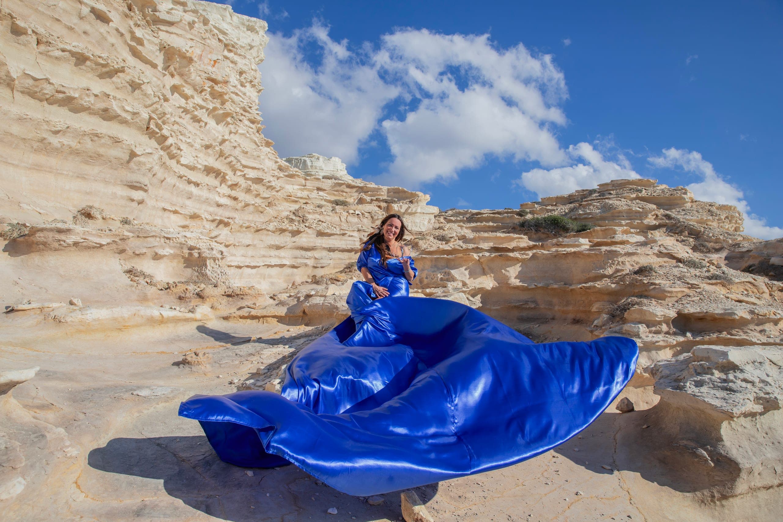 Flying dress photography: woman in a flowing blue dress on the Cyprus coast